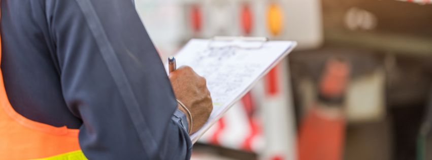 Man in orange safety vest with a clipboard and pen.