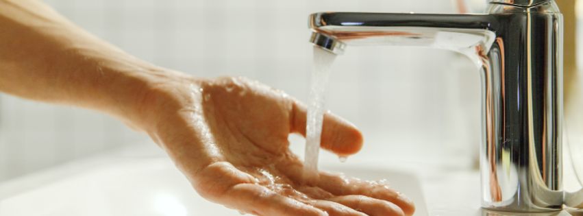 Hand feeling water coming out of facet.
