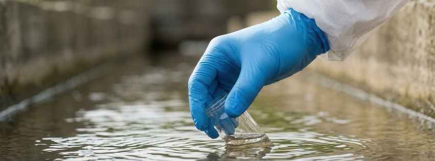 Hand scooping water into a test tube.