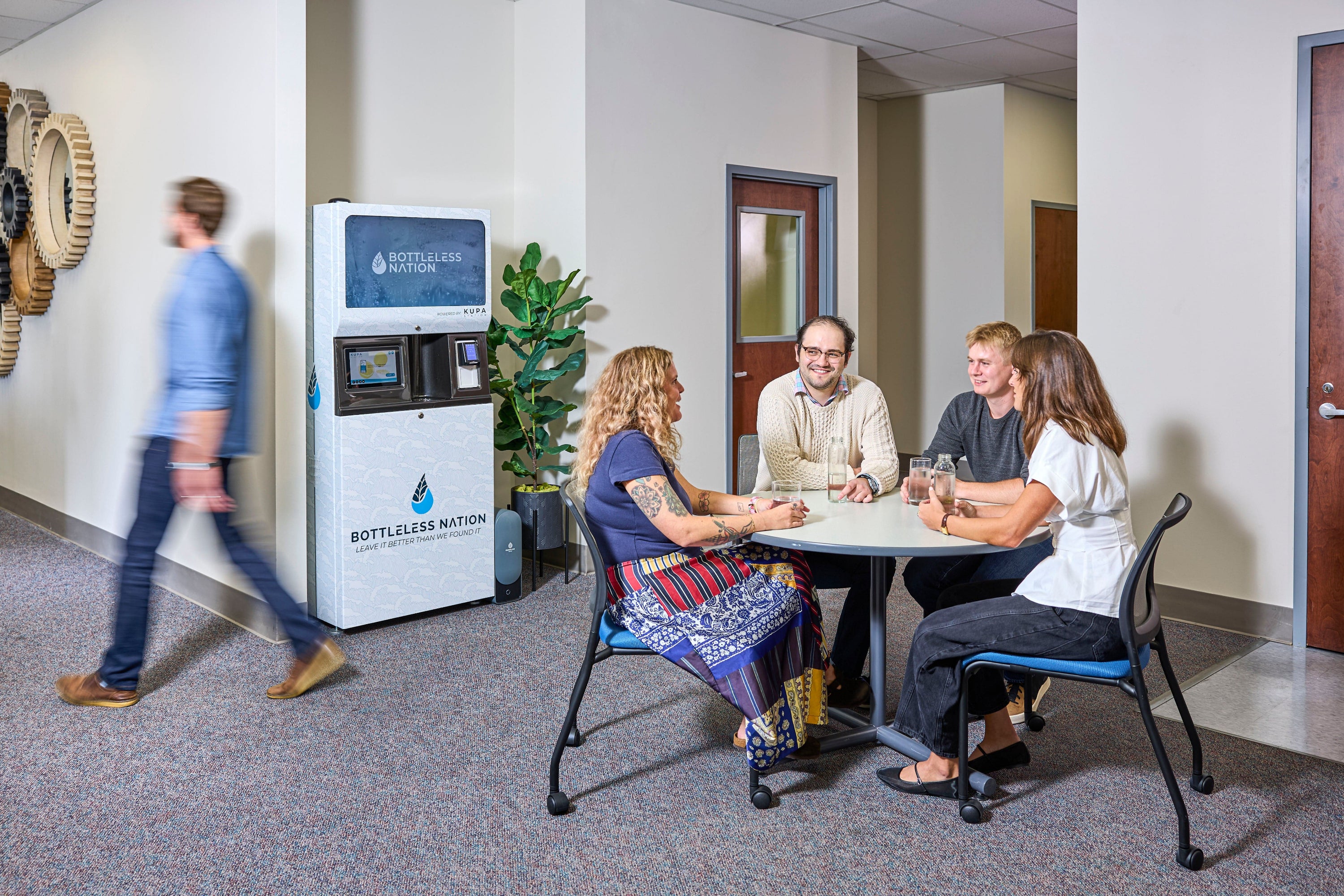 People sitting around a table in an office setting with a water dispenser in the background.